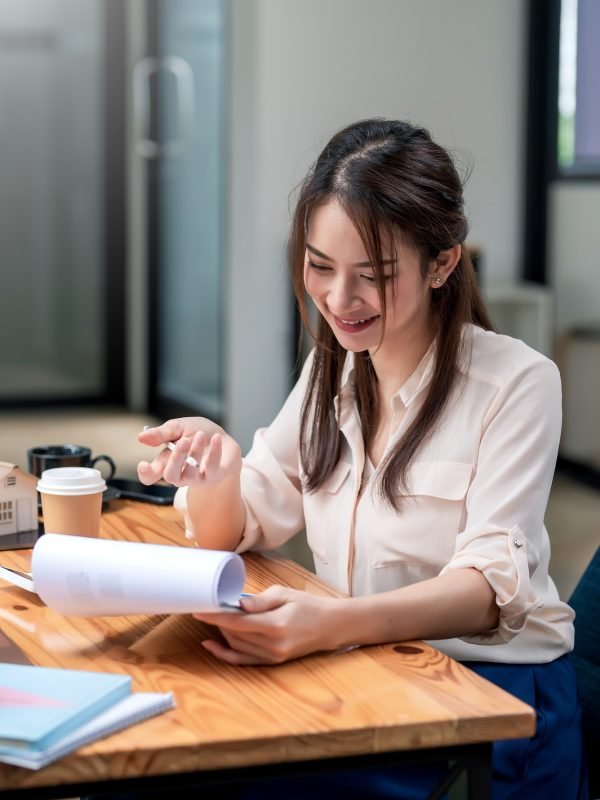Happy young Asian businesswoman to work holding documents at the office.