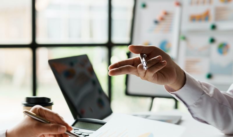 Two business people point to graphs and charts to analyze market data, balance sheet, account, net p