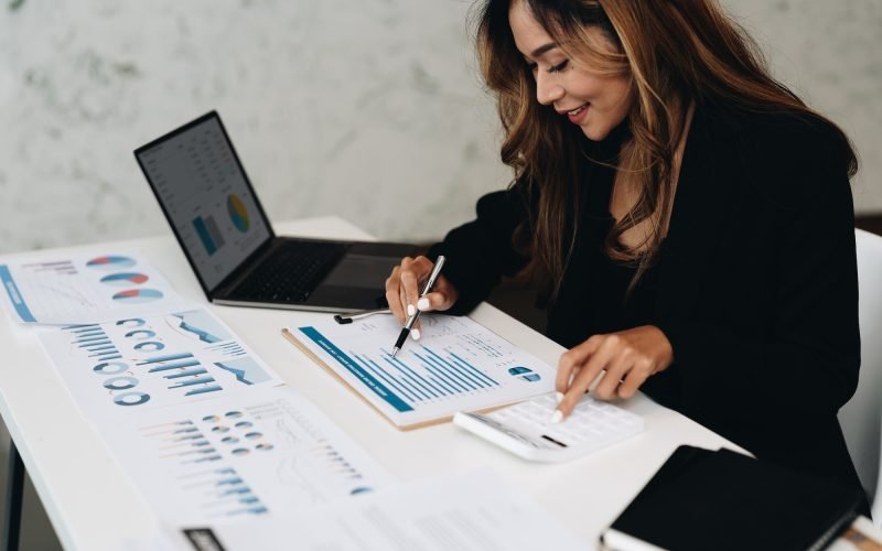 usiness analyzing investment charts with calculator laptop. Accounting and technology in office