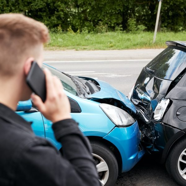 Young Male Motorist Involved In Car Accident Calling Insurance Company Or Recovery Service