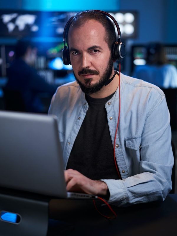 Vertical Portrait looking at camera of a Stock Market Trader Working Investment Charts,