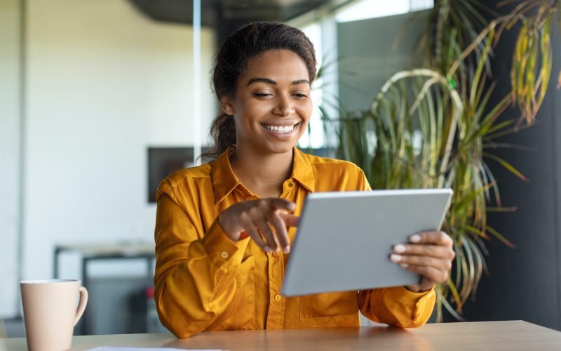 Modern technologies in business. Happy black businesswoman using modern digital tablet, working Modern technologies in business. Happy black businesswoman using modern digital tablet, working