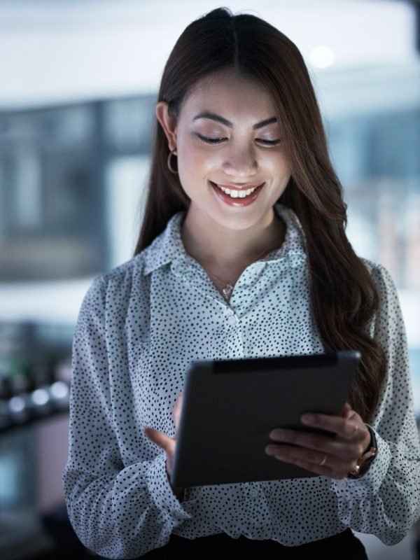 Shot of a young businesswoman using a digital tablet in an office at night