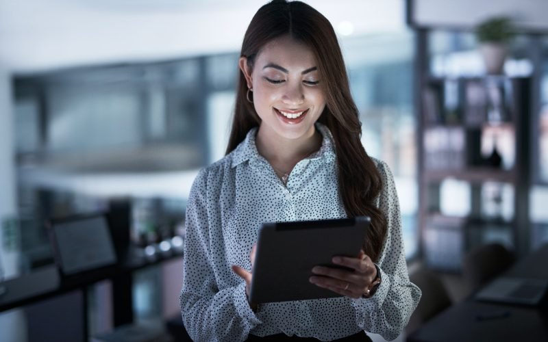 Shot of a young businesswoman using a digital tablet in an office at night Shot of a young businesswoman using a digital tablet in an office at night