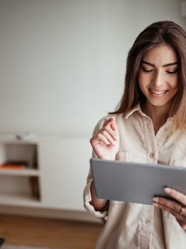 Smiling pretty young asian lady in casual use tablet for control smart home, enjoy study and work