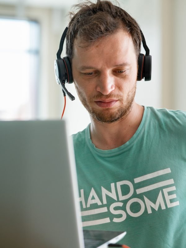 young programmer works from home using laptop and headphones