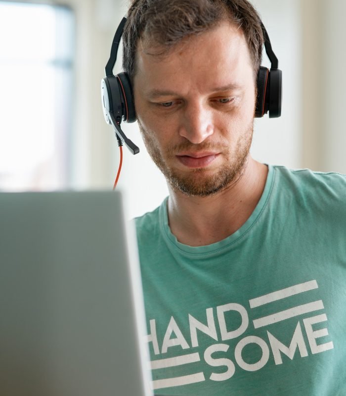 young programmer works from home using laptop and headphones