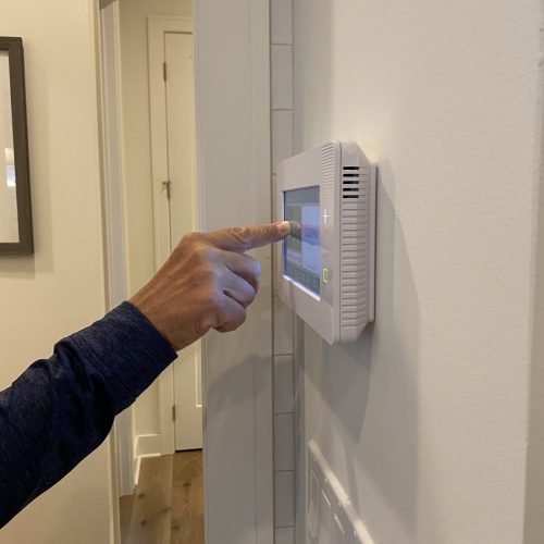 A man is setting his alarm on a security panel in his smart home.