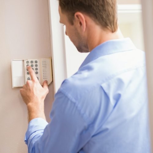 Man arming a home alarm on the wall