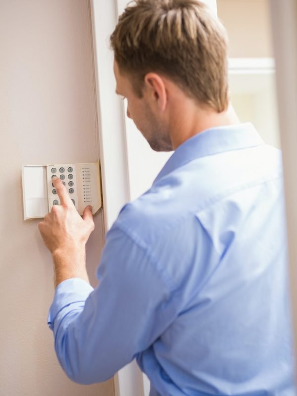 Man arming a home alarm on the wall