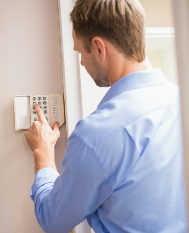 Man arming a home alarm on the wall