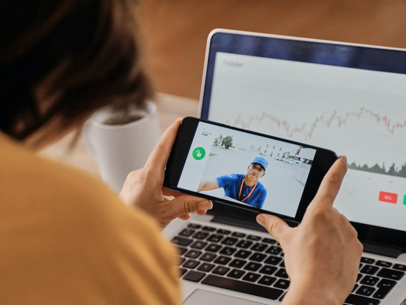 Woman watching delivery man on security camera video on mobile phone while working at home office