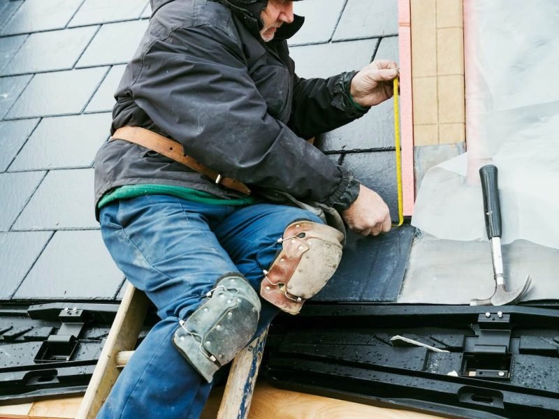 a-man-at-the-top-of-a-ladder-on-a-house-roof-fixing-tiles-on-a-dormer-roof-
