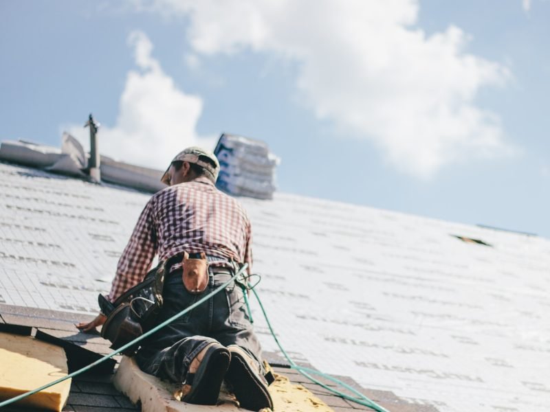Roofer adding shingles to the roof of a house