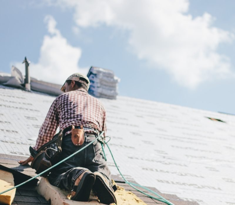 Roofer adding shingles to the roof of a house