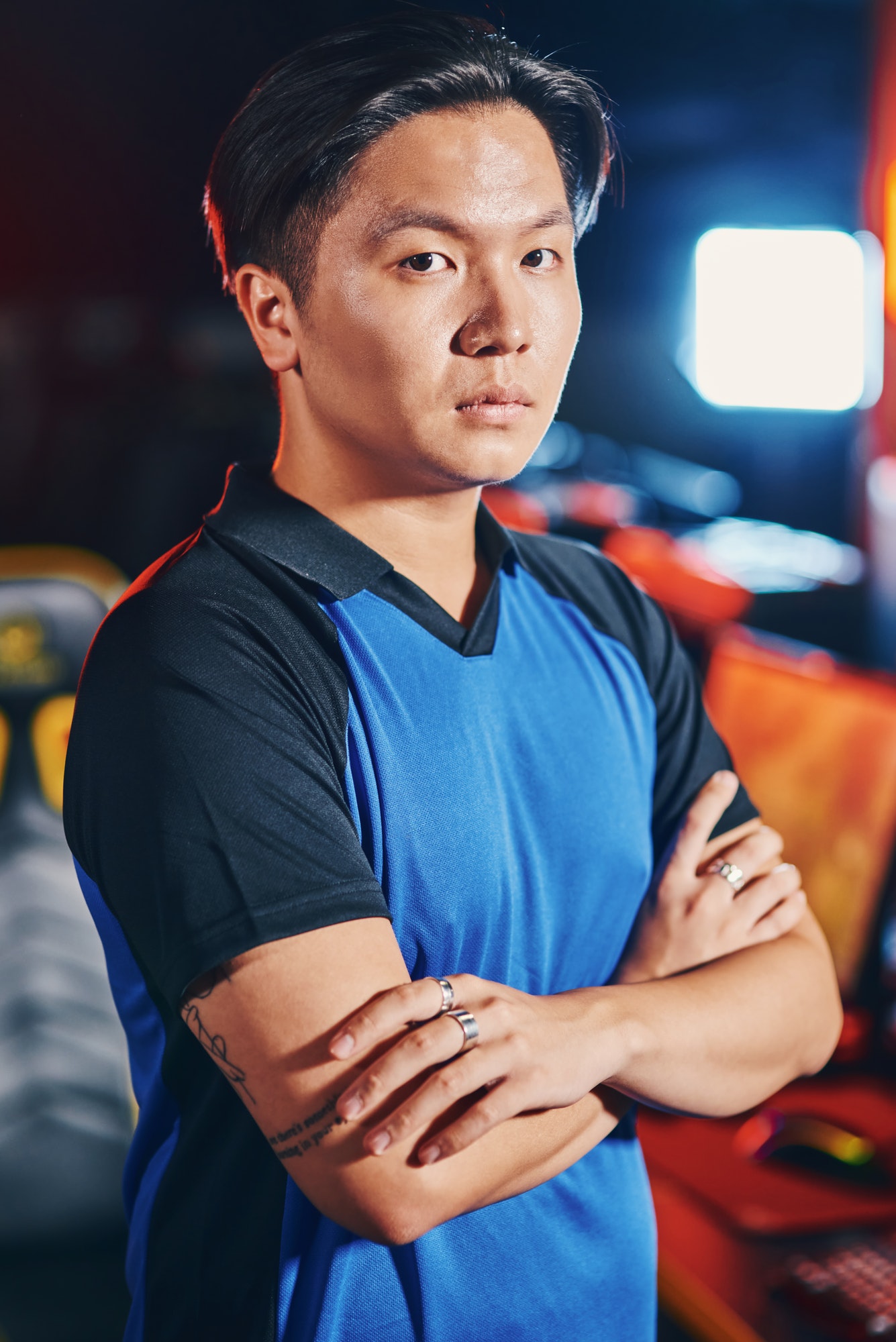 Vertical shot of young asian guy, male cyber sport gamer keeping arms crossed and looking at camera