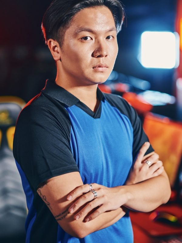 Vertical shot of young asian guy, male cyber sport gamer keeping arms crossed and looking at camera