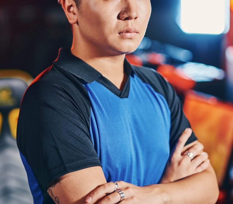 Vertical shot of young asian guy, male cyber sport gamer keeping arms crossed and looking at camera