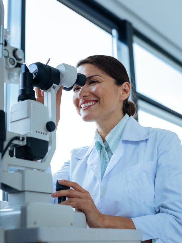 Cheerful female doctor looking into the microscope