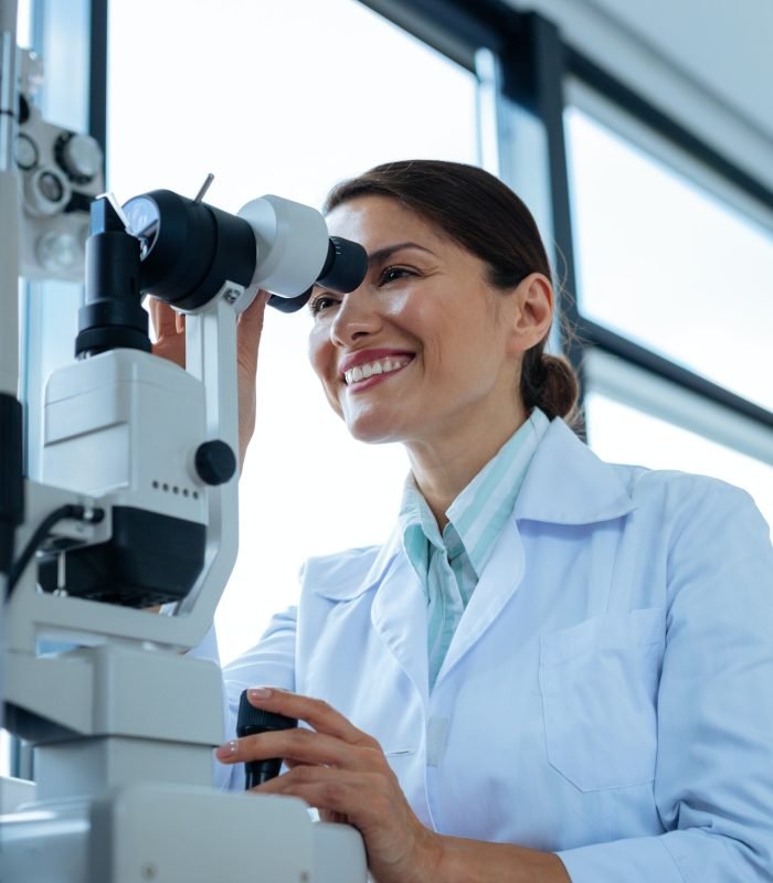 Cheerful female doctor looking into the microscope