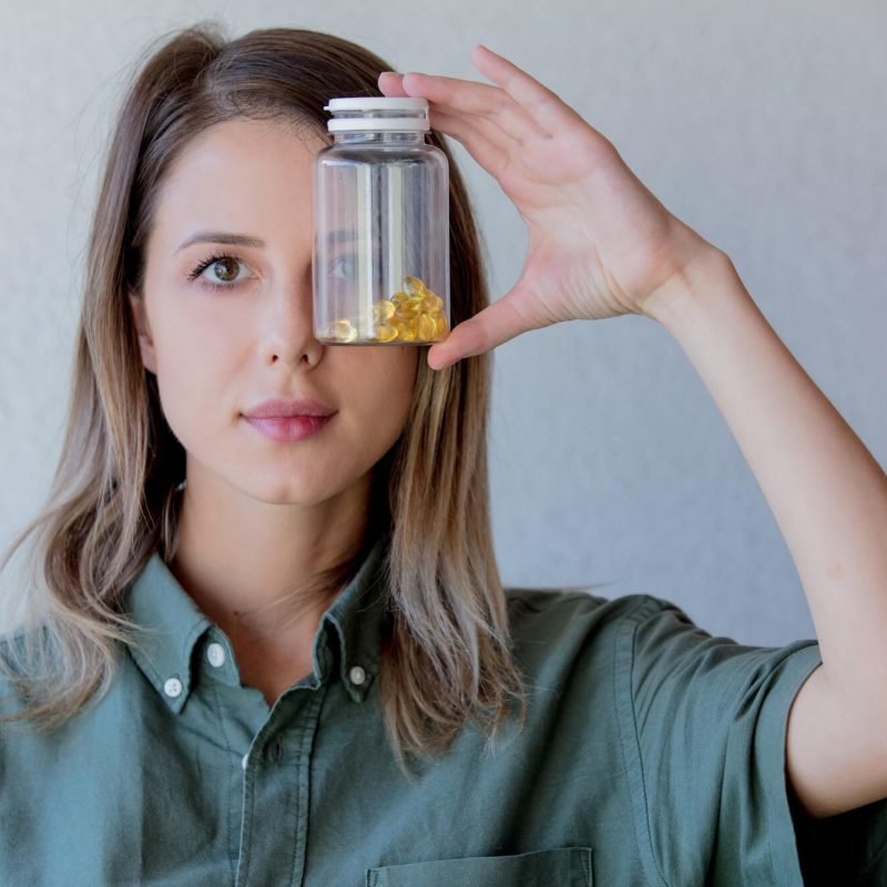 woman-keeps-transparent-jar-with-pills-at-eye-level