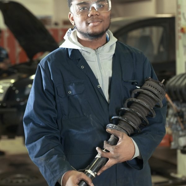 Student carrying car part in garage