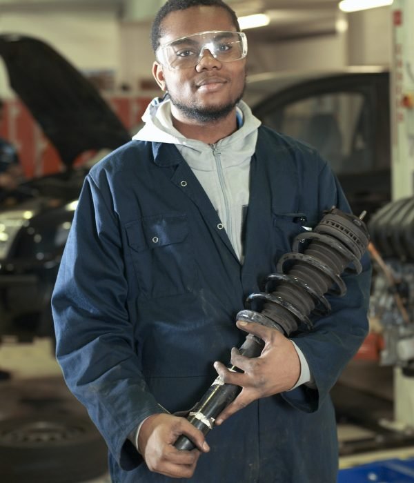 Student carrying car part in garage