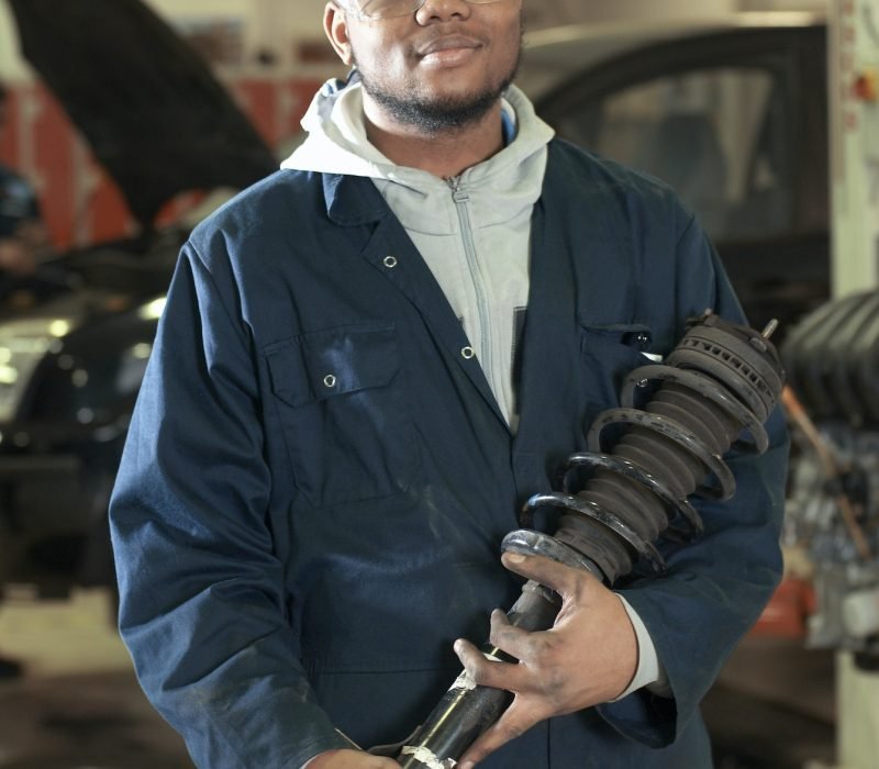 Student carrying car part in garage