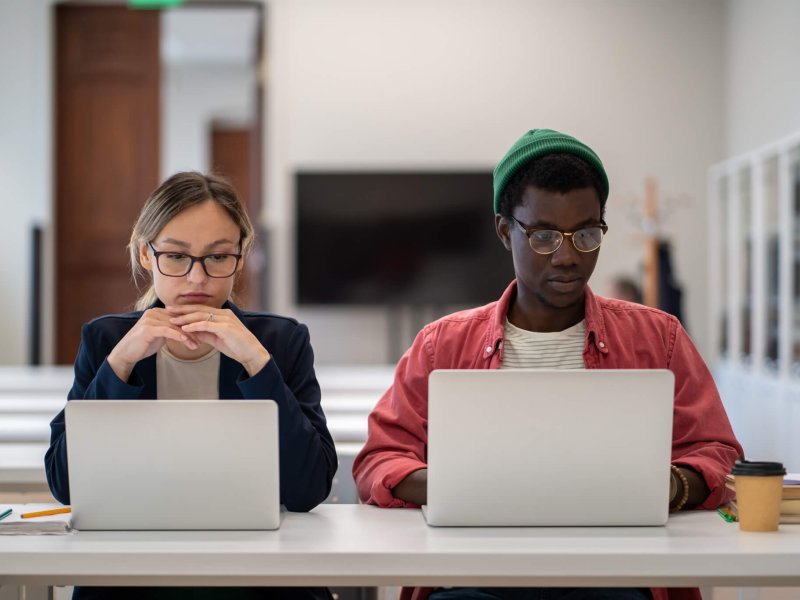 Diverse multiethnic focused students studying foreign language training center classroom with laptop