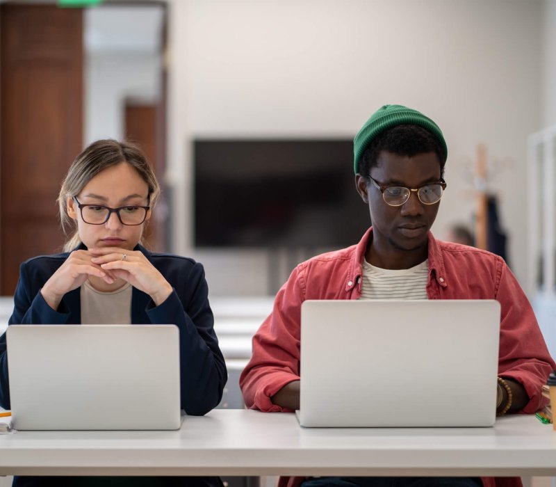 Diverse multiethnic focused students studying foreign language training center classroom with laptop