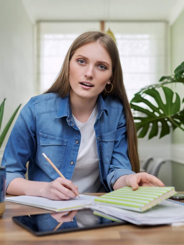 Online training, female teenager sitting at home looking at webcam, Canadian flag on table
