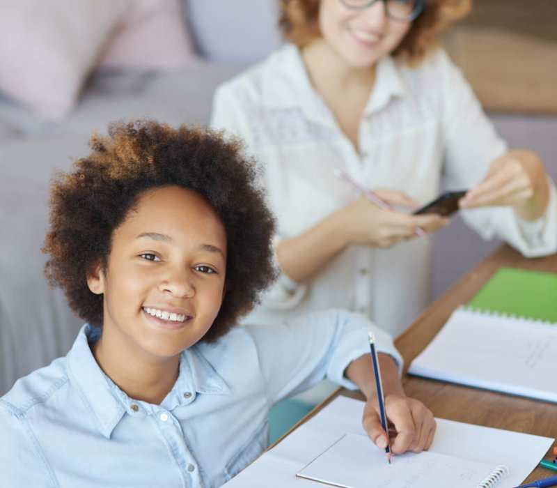 Radiate happiness. Happy mixed race teen schoolgirl smiling at camera while having a lesson with