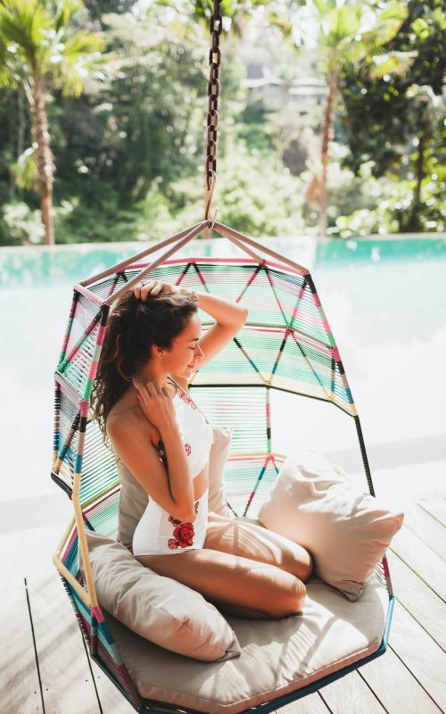 woman-in-white-swimsuit-enjoying-in-hanging-chair-swing-on-poolside-in-luxury-hotel-
