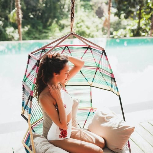 woman-in-white-swimsuit-enjoying-in-hanging-chair-swing-on-poolside-in-luxury-hotel-