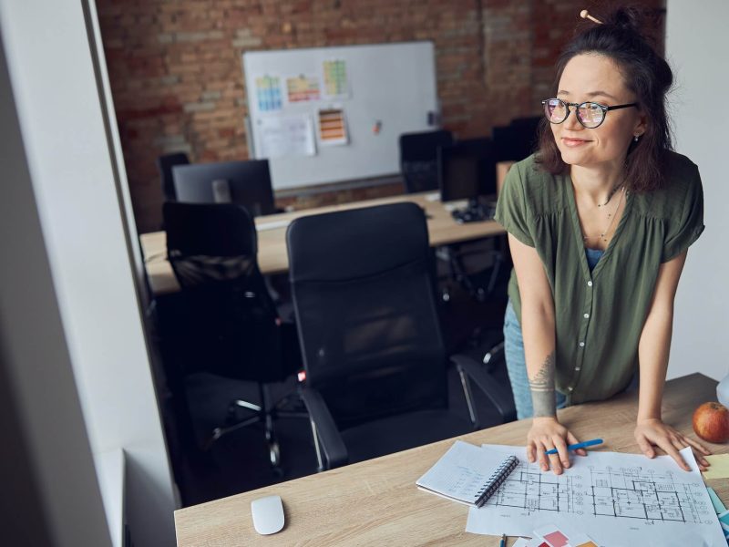 interior-designer-or-architect-in-casual-wear-with-messy-hairdo-smiling-aside-while-working-on-a