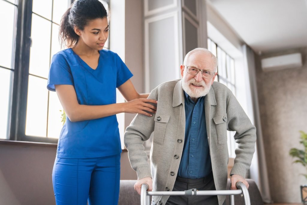 Handicapped man using walker - rehabilitation at home. Nurse helping disabled man using walker