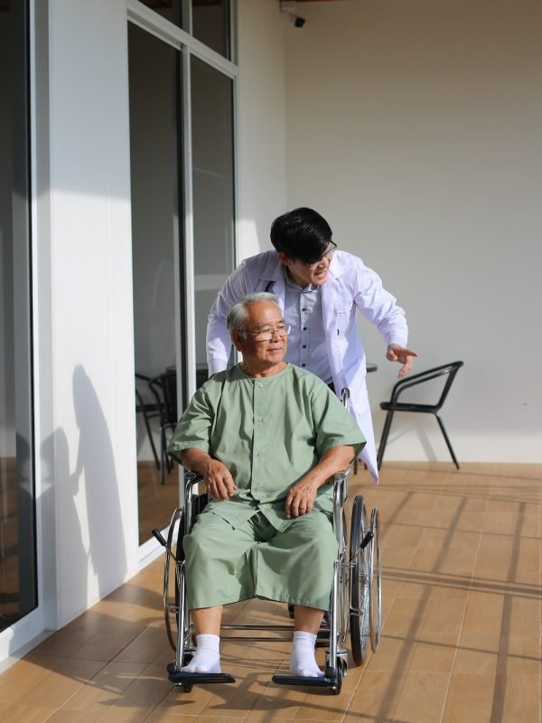 Caretaker Helping Senior Man with Disability at Checkup Visit