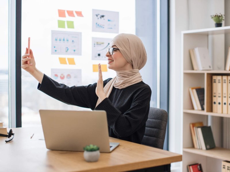 Assistant joining online meeting via phone at office desk