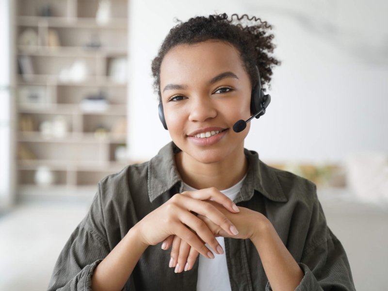 Virtual assistant. Young afro woman in headset is operator of client support service from home.