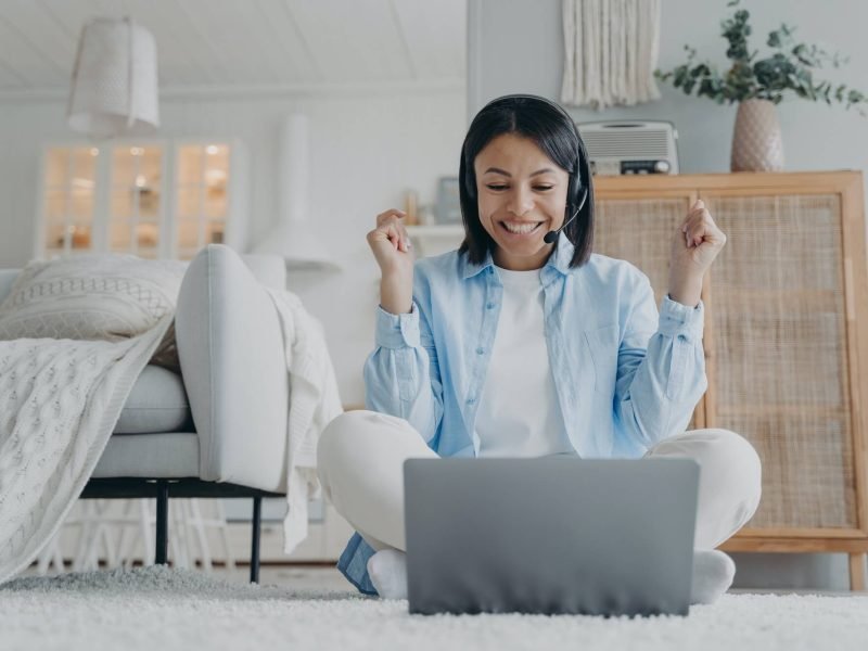 Friendly woman coach in headset working online on laptop conducts webinar at home. Elearning